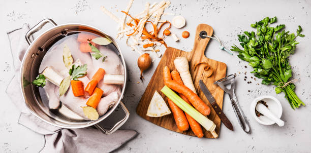 Cooking - chicken stock (broth or bouillon) with vegetables Cooking - preparing chicken stock (broth or bouillon) with vegetables in a pot. Kitchen - grey concrete worktop scenery from above (top view, flat lay). homemade food stock pictures, royalty-free photos & images