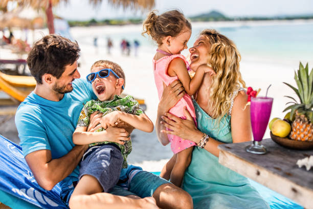 istock Cheerful parents having fun with their kids on a deck chair at beach. 1214443764
