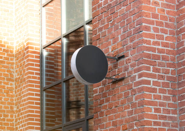 Blank black outdoor round box mockup brick wall mounted. Empty street signage hanging on emporium mock up. Clear circular banner for club restaurant mokcup template.