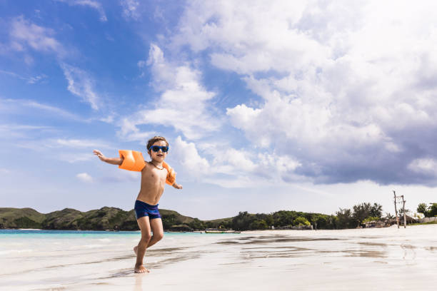 ビーチで夏の日に楽しんで幸せな小さな男の子。 - water wings ストックフォトと画像