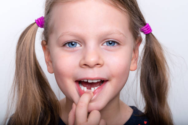Child girl dropped the first milk tooth - preschooler girl with open mouth without milk tooth