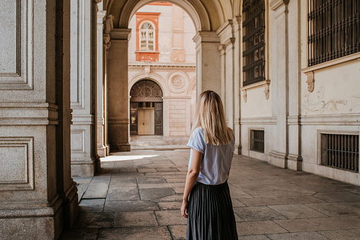 A beautiful woman with blond hair walks through the streets of the city. Girl enjoy holidays in Europe. Beautiful historical architecture. Italian weekend. Travel to Turin, Italy. Adventure lifestyle