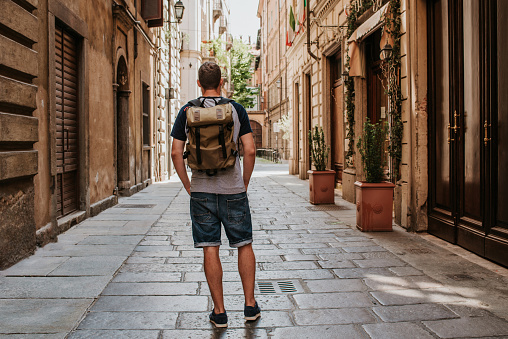 A man with a backpack walks through the streets of the city. Tourist enjoy holidays in Europe. Beautiful old historical architecture. Italian weekend. Travel to Turin, Italy. Adventure lifestyle