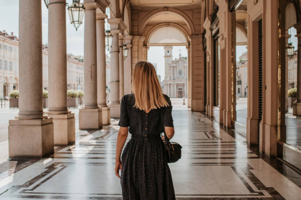 A beautiful woman with blond hair walks through the streets of the city. Girl enjoy holidays in Europe. Beautiful historical architecture. Italian weekend. Travel to Turin, Italy. Adventure lifestyle stock photo