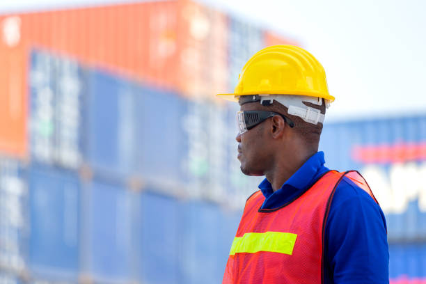istock Worker man in hardhat and safety vest standing at containers cargo, Foreman control loading containers box from cargo 1214448320