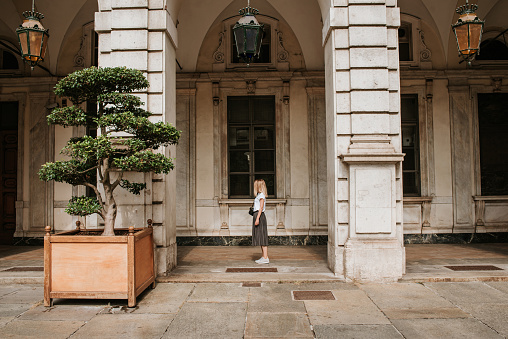 A beautiful woman with blond hair walks through the streets of the city. Girl enjoy holidays in Europe. Beautiful historical architecture. Italian weekend. Travel to Turin, Italy. Adventure lifestyle