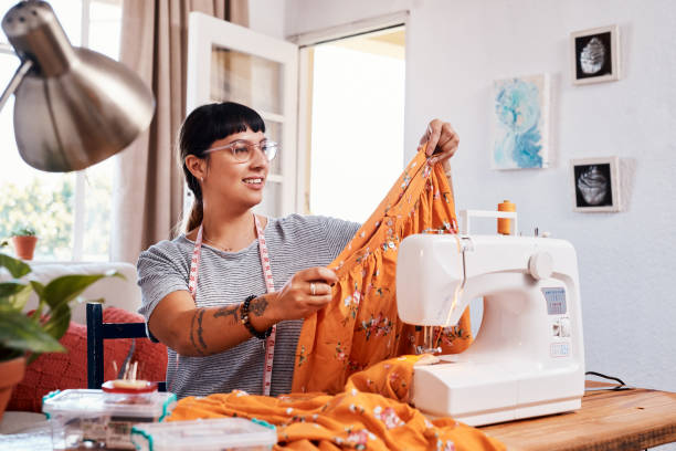 This skirt will be trending as soon as I post it Shot of a beautiful young woman working on a garment at home woman stitching stock pictures, royalty-free photos & images