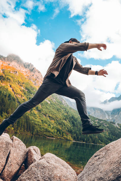 istock man jumping from rock at lake beach in mountains 1214450346