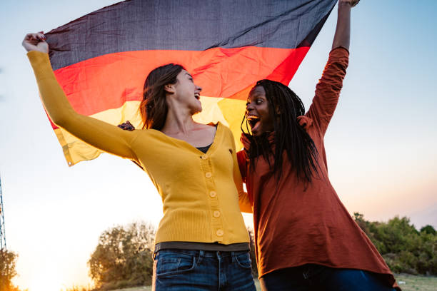 zwei multiethnische frauen mit deutscher flagge - tag der deutschen einheit stock-fotos und bilder