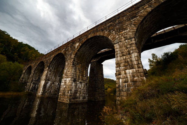 Historical stone bridge at old circum railway of Transsiberian at Baikal lake in September with autumn leaves on water at cloudy day