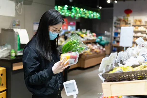 Asian woman in supermarket wearing protective medical mask during Coronavirus, Covid-19 outbreak. China, life is slowly returning to normal.