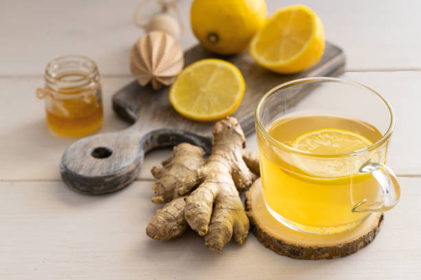 istock Ginger tea on lemon  on glass mug on light wooden background for help relieve cold and flu symptoms. 1214453301
