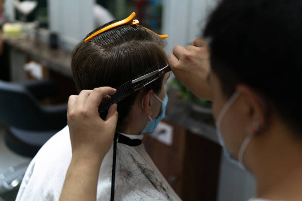 leben in asien unter druck während des neuartigen coronavirus, covid-19. kaukasischer männlicher und chinesischer friseur trägt medizinische maske, um sich vor viren zu schützen. - chinese culture china chinese ethnicity human face stock-fotos und bilder