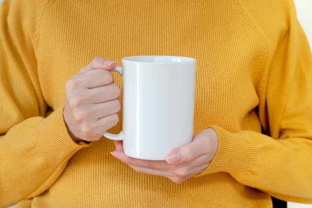 istock Mug mockup. Women's hands holding mug with blank space for your text or promotional content. 1214455315