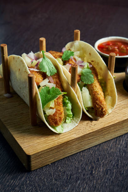 istock Appetizing Mexican tacos with fried chicken, cabbage, onions and parsley in special stands. Traditional mexican cuisine 1214455385