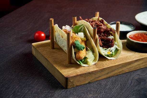 istock Appetizing Mexican tacos with fried chicken and stewed beef, cabbage, onions and parsley in special stands. Traditional mexican cuisine 1214455550