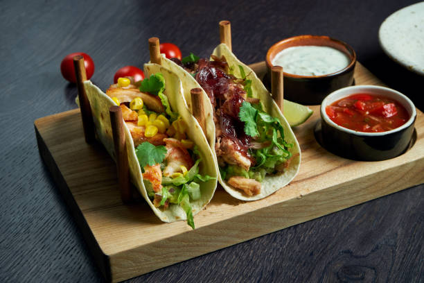 istock Appetizing Mexican tacos with fried chicken and stewed beef, cabbage, onions and parsley in special stands. Traditional mexican cuisine 1214455557