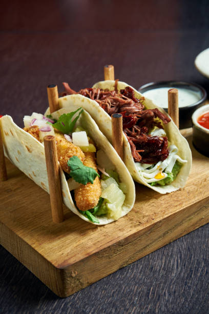 istock Appetizing Mexican tacos with fried chicken and stewed beef, cabbage, onions and parsley in special stands. Traditional mexican cuisine 1214455595