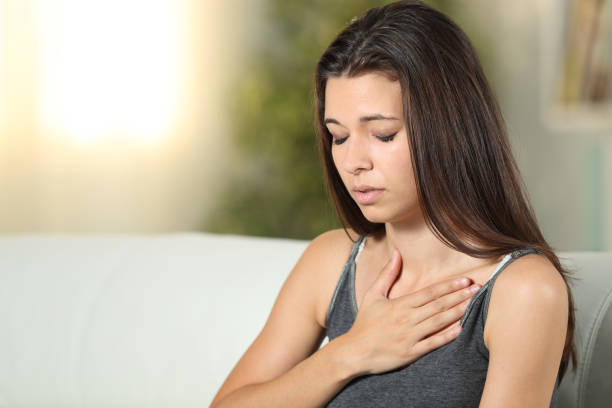 Girl having respiration problems touching chest Girl having respiration problems touching chest sitting on a couch in the living room at home inhaling stock pictures, royalty-free photos & images