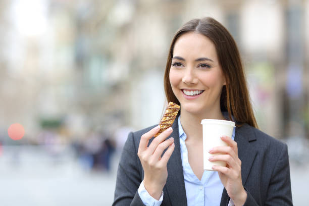 istock Executive holding snack bar and takeaway coffee in the street 1214455873