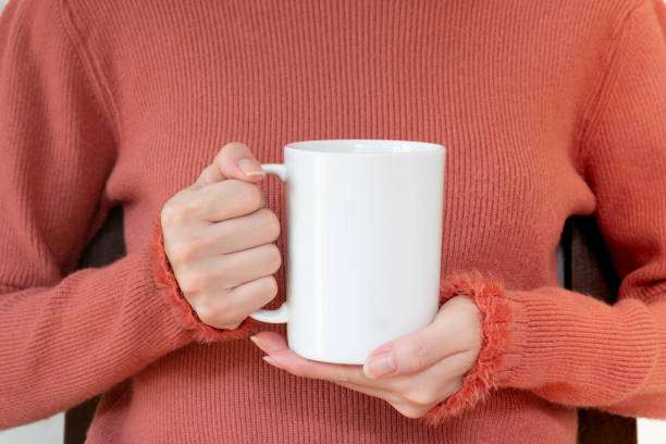 istock Mug mockup. Women's hands holding mug with blank space for your text or promotional content. 1214456434