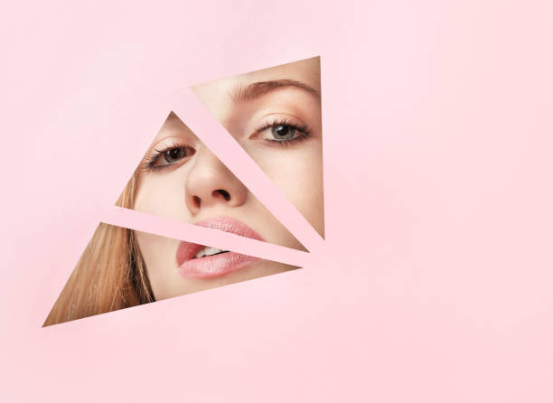 istock Beautiful female face with makeup into paper holes 1214456931