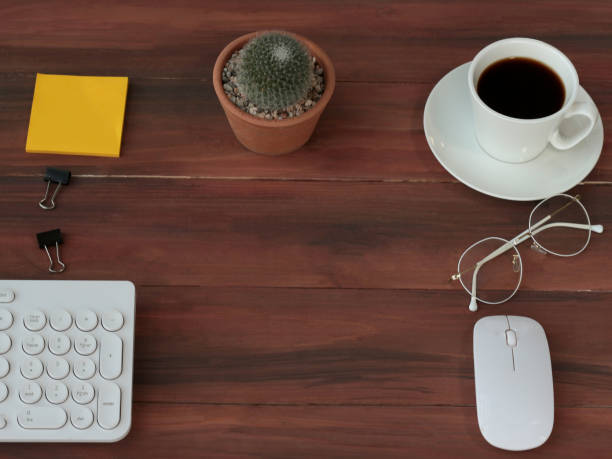 istock Wooden office table workspace from top view above with copy space, working desk with mix of note book and other office supplies, cup of coffee and cactus 1214456973