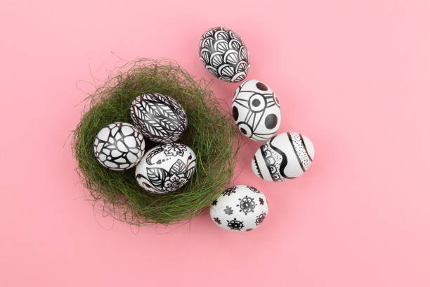 istock Three easter eggs are painted in black and white lie in a green nest 1214457064
