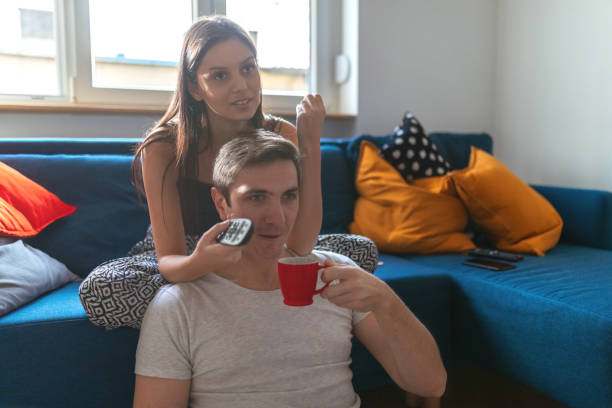 istock Changing channels on the sofa, her boyfriend on the floor 1214457114