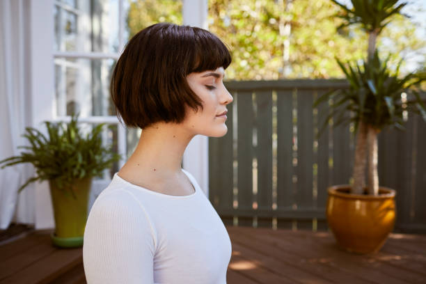 istock Young woman meditating on her patio while practicing yoga 1214457489
