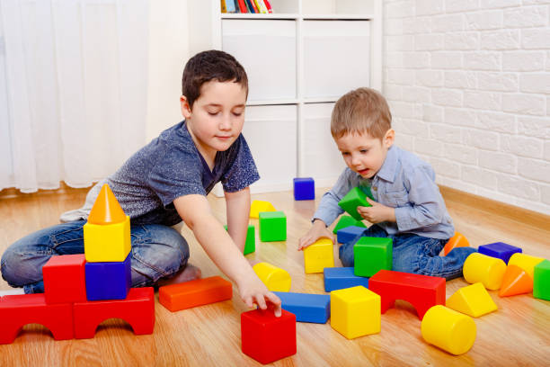 istock Cute children playing with constructor on floor at home 1214458704
