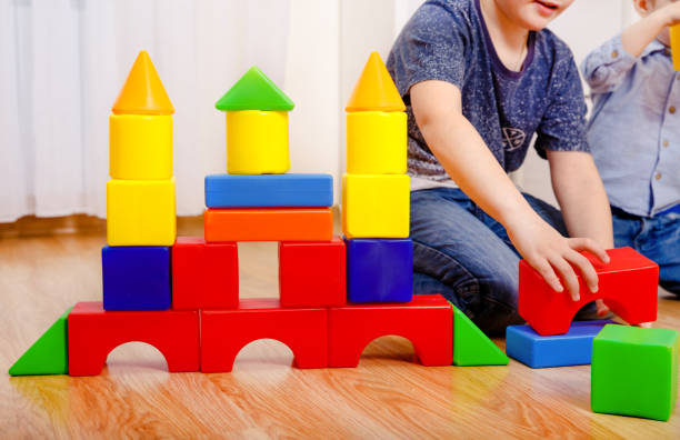Children playing with constructor on floor at home. Hands close up
