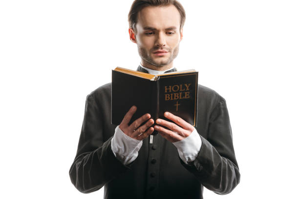 istock serious, concentrated catholic priest reading holy bible isolated on white 1214461915
