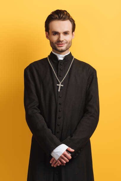 istock young catholic priest smiling at camera while standing isolated on yellow 1214461947