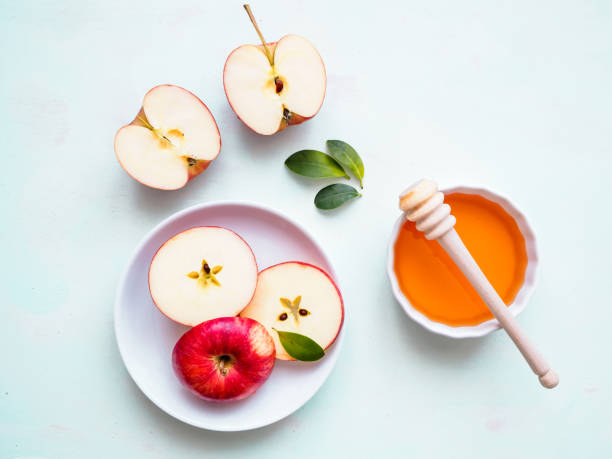 istock Red apple cut in half on a plate and honey in a white bowl on a neutral background, flat lay 1214463740
