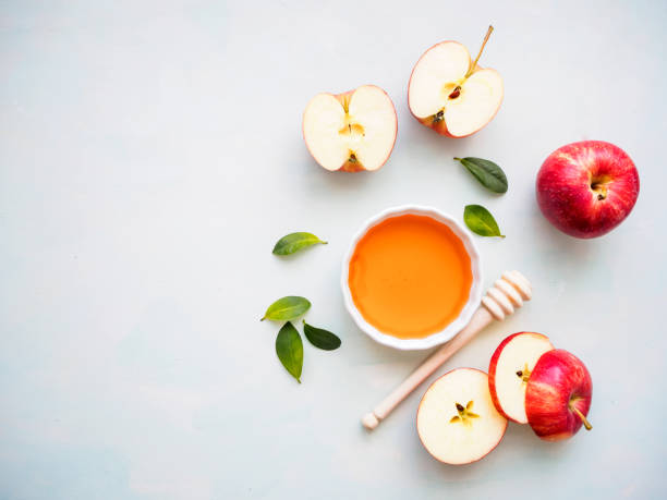 istock Red halved apple and honey on a light green background, flat lay 1214463892