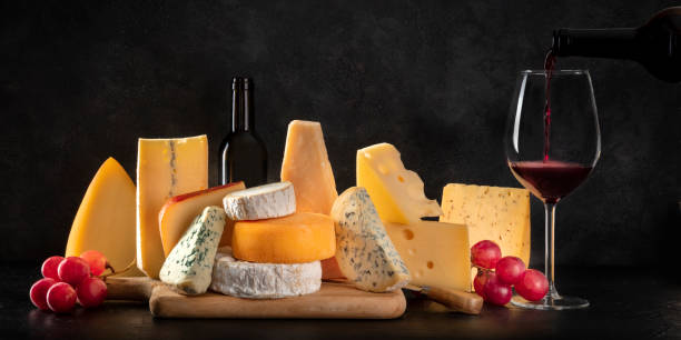 istock Cheese panorama, many different types of chees with grapes and pouring wine, a side view on a dark background with copy space 1214465723