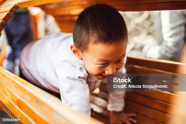 Cute Asian Toddler Having Fun Trying To Climb On A Jungle Gym Stock Photo - Download Image Now
