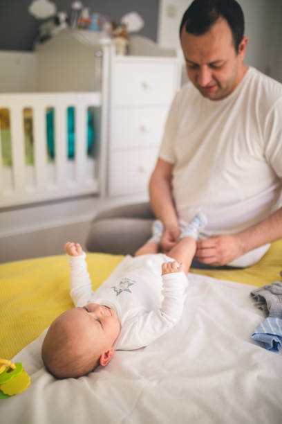 istock Father Changing Diaper To His Son 1214468230