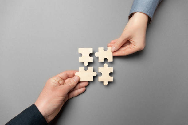 istock Two hands connect puzzles on a grey background. Cooperation and teamwork in business. Collaboration people for success 1214468232