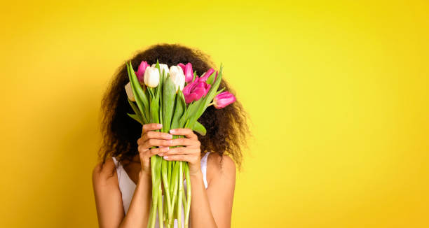 istock Young african woman with tulips bouquet 1214473065