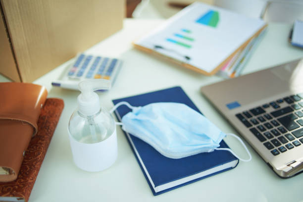 istock medical mask and hand disinfectant on table in home office 1214473436