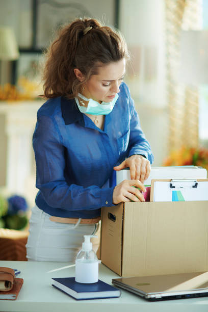 istock modern woman with mask transporting stuff to home office 1214474597