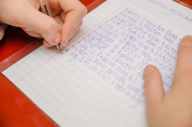 istock girl does a task in English, writes in a notebook close-up 1214475622