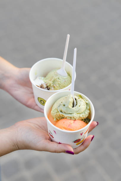 istock hands hold paper cup with ice cream. Ice cream pistachios and mango 1214476394