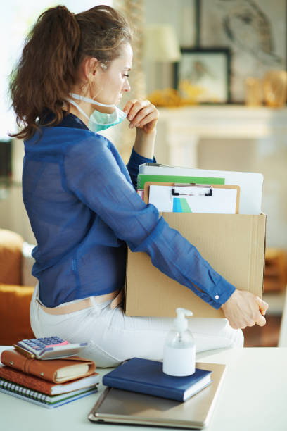 istock modern woman with mask transporting stuff to home office 1214476449