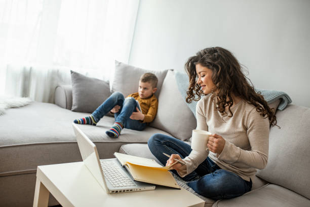 istock Young mother sitting at table and using laptop at home. 1214476670