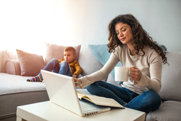 istock Young mother sitting at table and using laptop at home. 1214477453