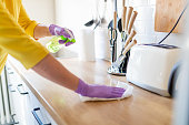 Hands in gloves disinfecting kitchen counter