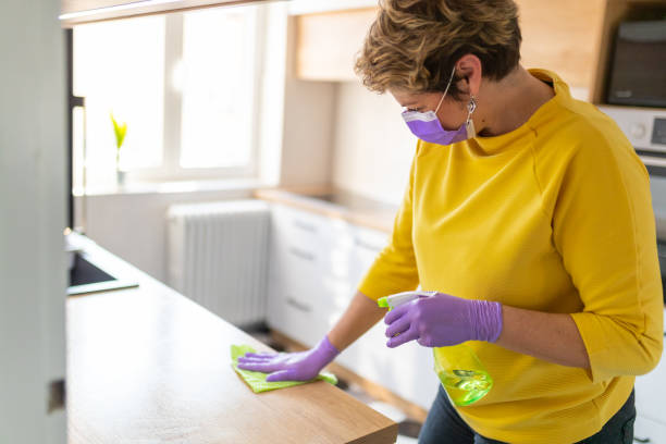 istock Middle aged woman cleaning kitchen counter with disinfectant 1214477725